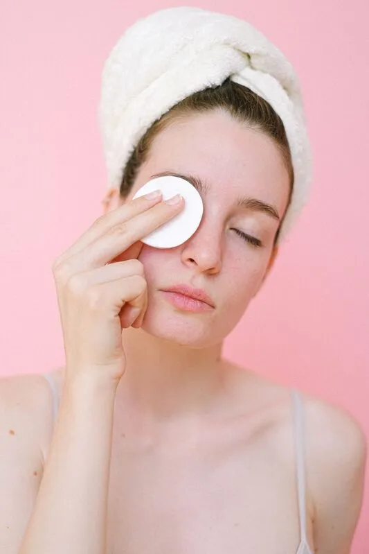 Mulher a remover a maquilhagem dos olhos com um disco de algodão