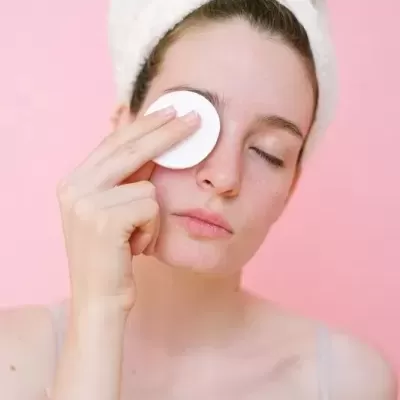 Mulher a remover a maquilhagem dos olhos com um disco de algodão