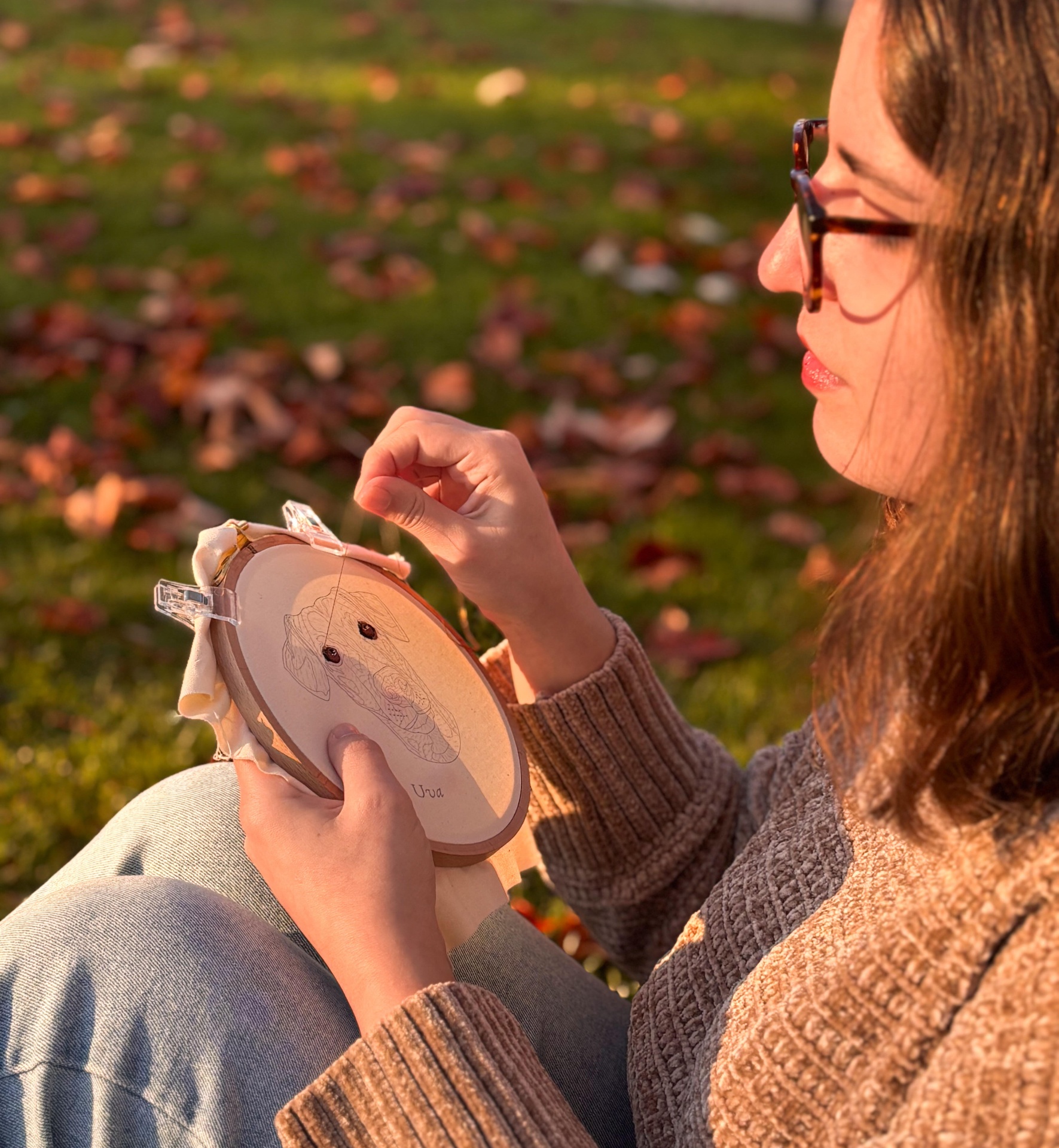 A Catarina, bordadeira da Pontos de Fada a bordar num jardim outonal.