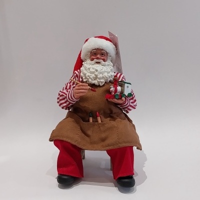 Pai Natal sentado a pintar os brinquedos.