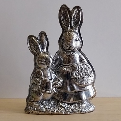 Coelha prateada com um cesto de flores e um coelhinho.